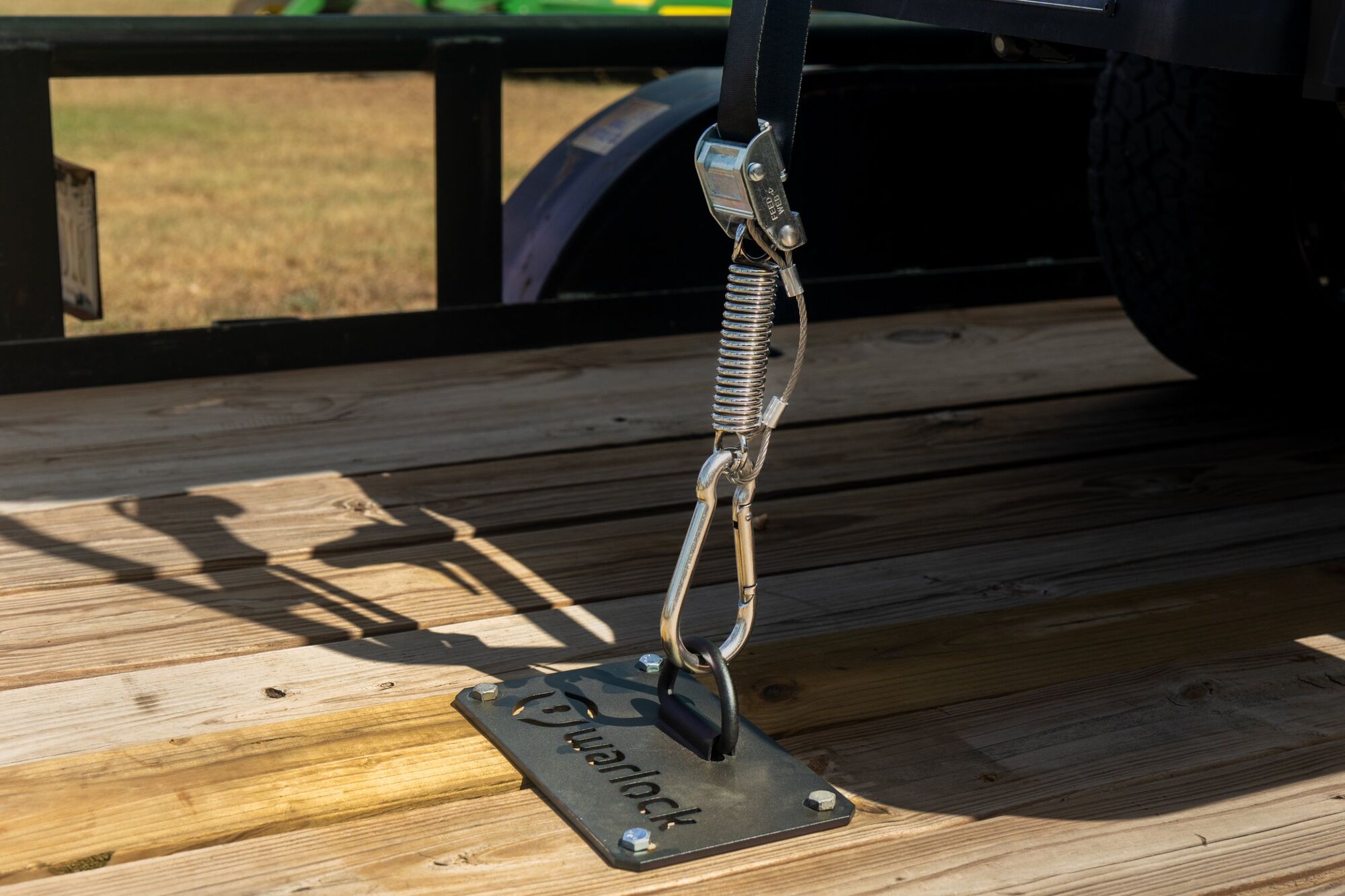 Sunlit wooden trailer deck with pasture behind